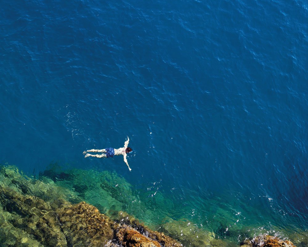 Uomo che nuota in Liguria al mare